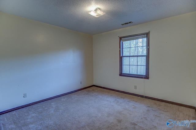 spare room featuring a textured ceiling, carpet floors, visible vents, and baseboards