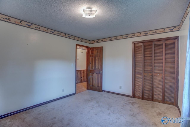 unfurnished bedroom with a textured ceiling, a closet, baseboards, and carpet flooring