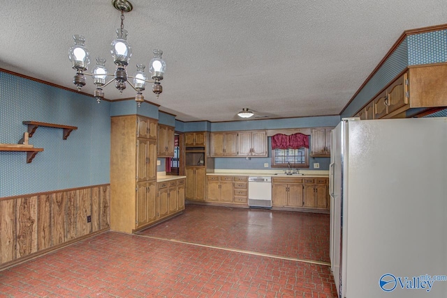 kitchen with white appliances, wainscoting, hanging light fixtures, brick floor, and light countertops