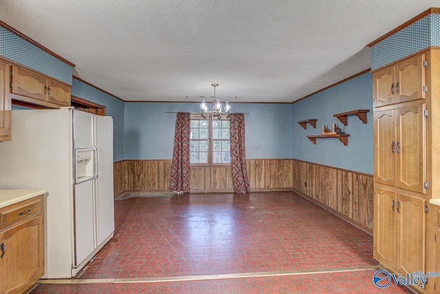 interior space featuring brick floor, crown molding, wainscoting, wooden walls, and a chandelier