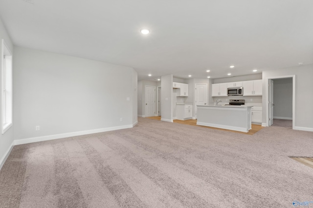 unfurnished living room with light carpet and sink