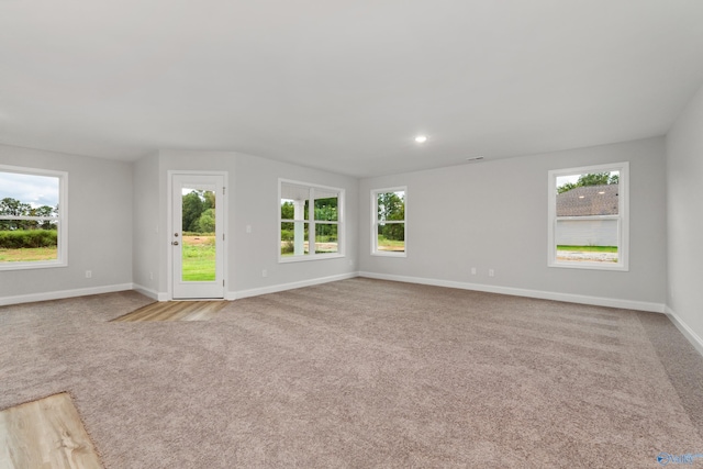 unfurnished living room featuring a healthy amount of sunlight and light carpet