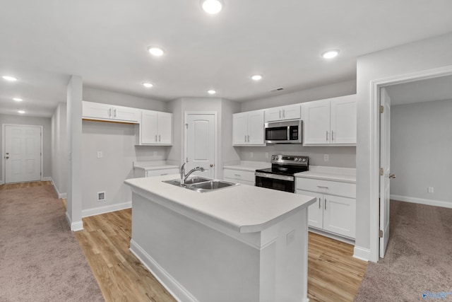 kitchen with white cabinetry, appliances with stainless steel finishes, a kitchen island with sink, and sink