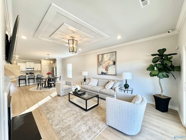 living room featuring light wood-type flooring, visible vents, baseboards, and ornamental molding