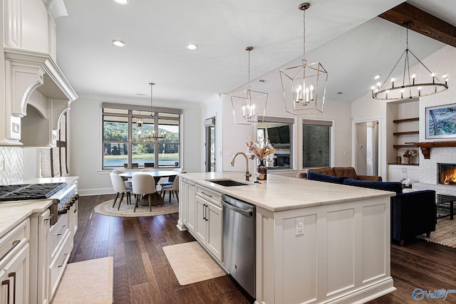 kitchen featuring a lit fireplace, dark wood-type flooring, a chandelier, a sink, and stainless steel appliances