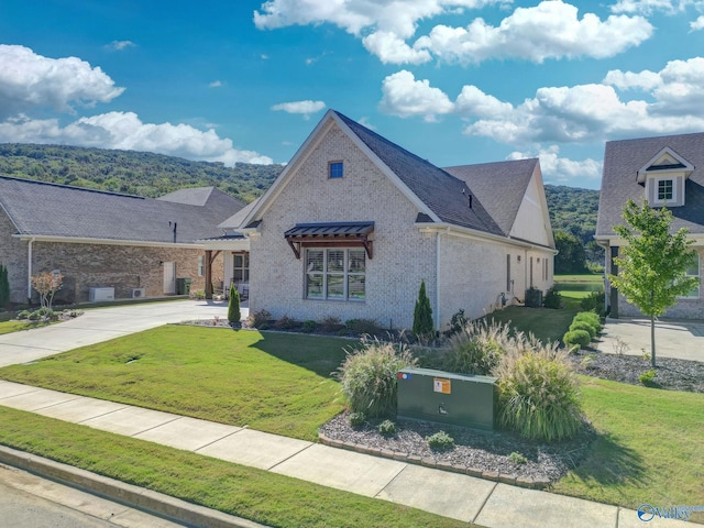 view of front of home with brick siding, a front lawn, and concrete driveway