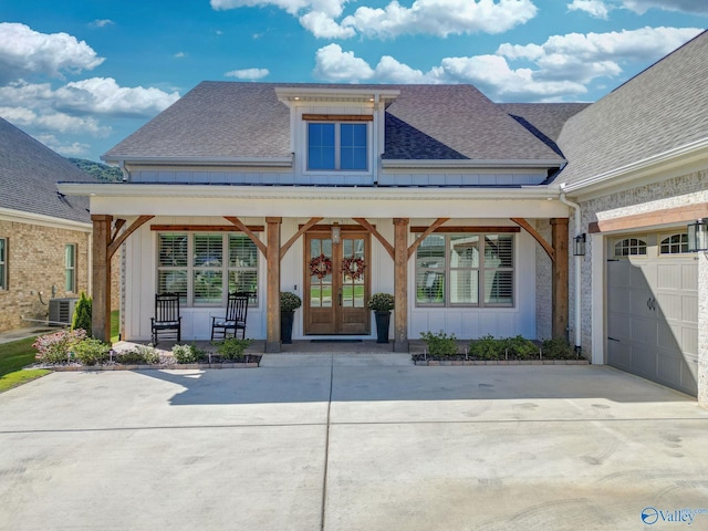 view of front of property with board and batten siding, driveway, french doors, roof with shingles, and central AC unit