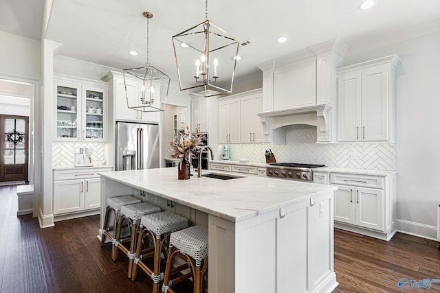 kitchen with tasteful backsplash, a center island with sink, a sink, white cabinets, and stainless steel appliances