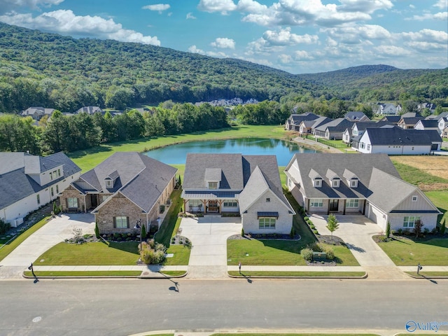 drone / aerial view featuring a residential view, a water and mountain view, and a forest view