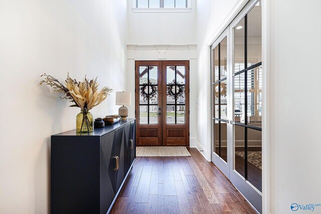 doorway with a healthy amount of sunlight, french doors, dark wood finished floors, and a towering ceiling