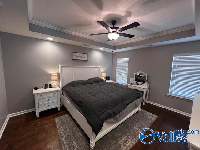 bedroom with dark wood-type flooring, ceiling fan, and a tray ceiling