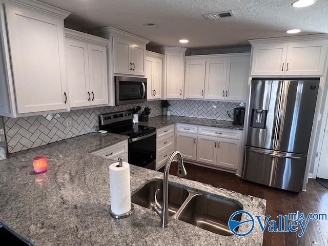 kitchen featuring stainless steel appliances, sink, white cabinets, and backsplash