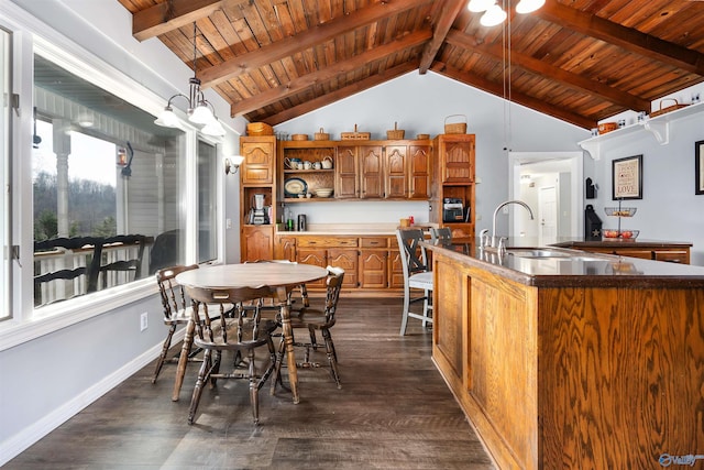 kitchen with brown cabinetry, dark countertops, pendant lighting, open shelves, and a sink