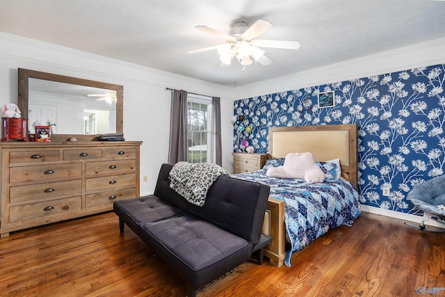 bedroom with dark wood-style flooring, crown molding, ceiling fan, baseboards, and wallpapered walls