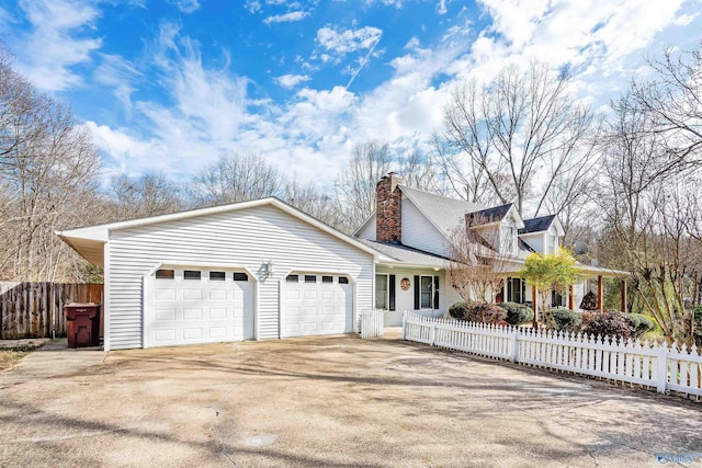 view of front of property featuring driveway, a fenced front yard, a garage, and a chimney