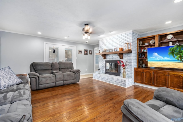 living area with ceiling fan, ornamental molding, wood finished floors, a fireplace, and recessed lighting