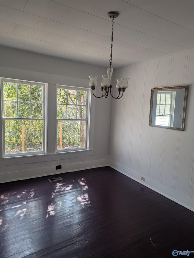 unfurnished room featuring visible vents, baseboards, dark wood-type flooring, and an inviting chandelier