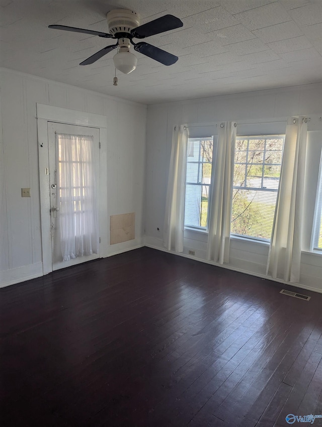 unfurnished room featuring visible vents, ceiling fan, and dark wood-style flooring