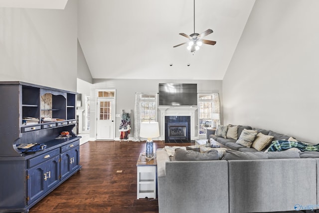 living room with ceiling fan, dark hardwood / wood-style floors, a tiled fireplace, and high vaulted ceiling