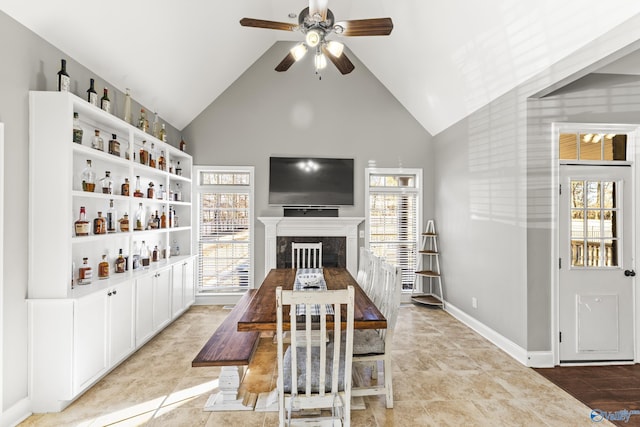 dining space featuring a fireplace, high vaulted ceiling, ceiling fan, and light tile patterned flooring