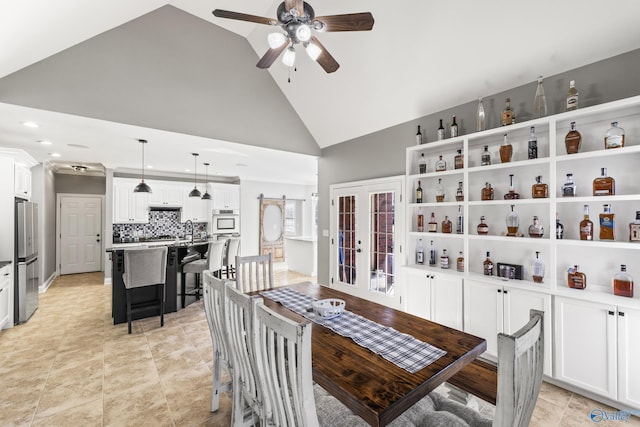 tiled dining space featuring sink, ceiling fan, high vaulted ceiling, a barn door, and french doors