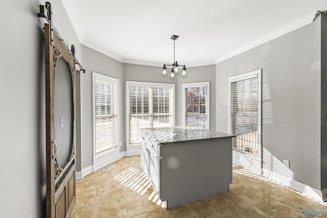 kitchen featuring a kitchen island, pendant lighting, white cabinetry, ornamental molding, and a barn door