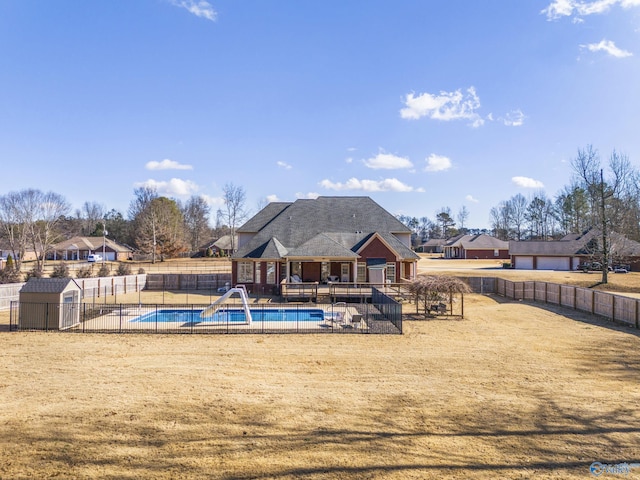 view of pool with a water slide, a yard, and a storage shed