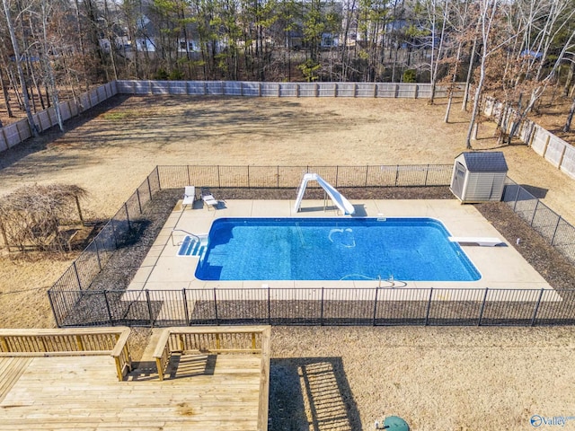 view of swimming pool with a water slide, a diving board, and a deck