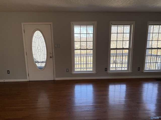 entryway with dark wood-style floors, a textured ceiling, and baseboards