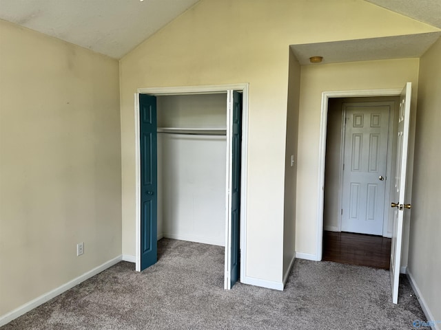 unfurnished bedroom featuring vaulted ceiling, a closet, carpet, and baseboards