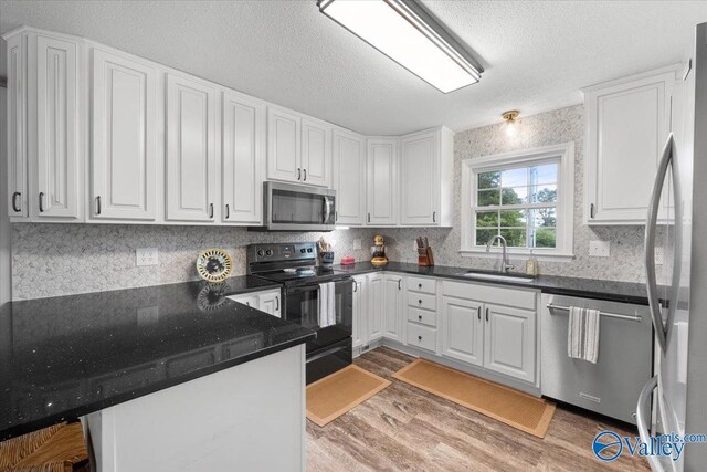 1762 Old Big Cove Rd SE, Owens Cross Roads, AL 35763 - kitchen with a peninsula, white cabinets, stainless steel appliances, a sink, and wood finished floors