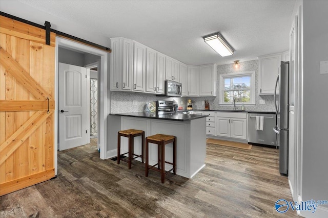 1762 Old Big Cove Rd SE, Owens Cross Roads, AL 35763 - kitchen with a peninsula, appliances with stainless steel finishes, wood finished floors, and a kitchen breakfast bar