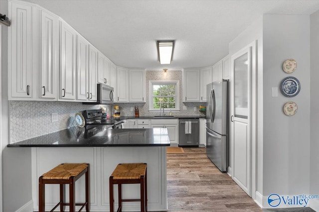 1762 Old Big Cove Rd SE, Owens Cross Roads, AL 35763 - kitchen featuring a peninsula, light wood-type flooring, appliances with stainless steel finishes, a sink, and dark countertops