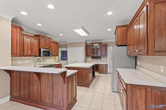 kitchen with brown cabinetry, a peninsula, appliances with stainless steel finishes, and ornamental molding