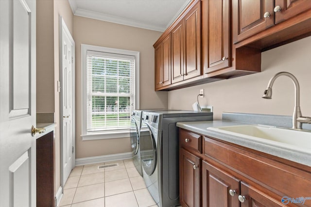 washroom with visible vents, washing machine and dryer, cabinet space, a sink, and ornamental molding