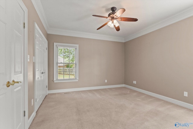 empty room featuring baseboards, ornamental molding, a ceiling fan, and light carpet