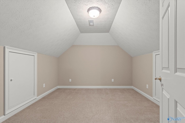 additional living space featuring a textured ceiling, light colored carpet, and baseboards
