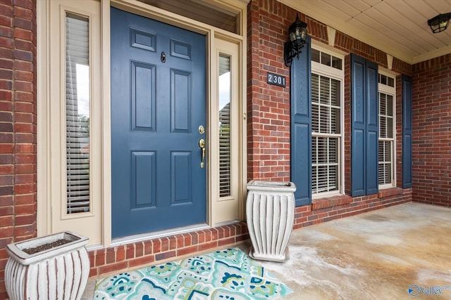 property entrance with a porch and brick siding