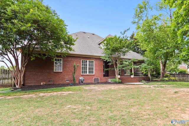 back of house featuring fence, a shingled roof, brick siding, crawl space, and a lawn