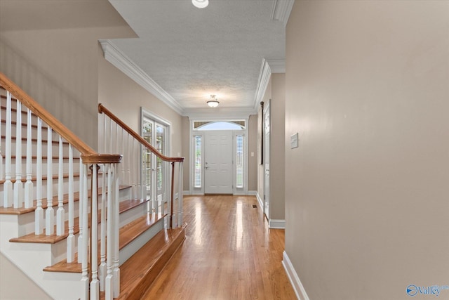 entrance foyer featuring crown molding, stairs, baseboards, a textured ceiling, and light wood finished floors