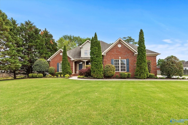 traditional home with a shingled roof, a front lawn, and brick siding