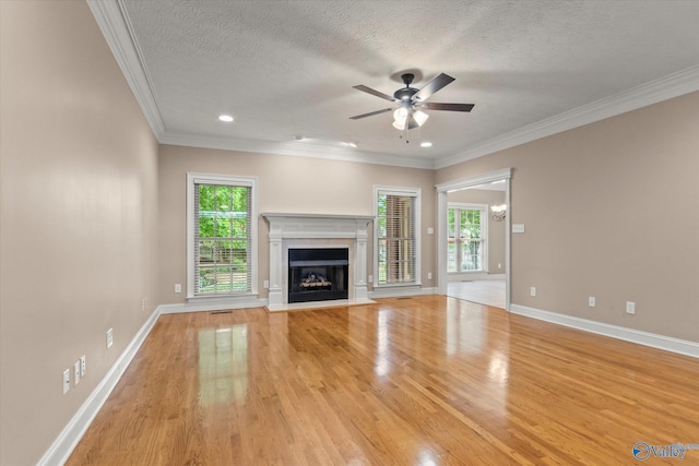 unfurnished living room with ceiling fan, crown molding, baseboards, light wood finished floors, and a premium fireplace