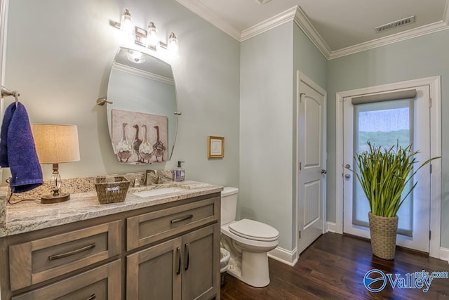 bathroom featuring toilet, ornamental molding, vanity, and wood-type flooring