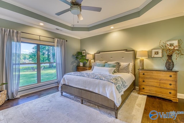 bedroom featuring hardwood / wood-style floors, a raised ceiling, and ornamental molding