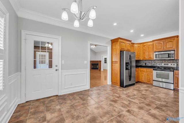 kitchen with decorative backsplash, ornamental molding, a notable chandelier, decorative light fixtures, and appliances with stainless steel finishes