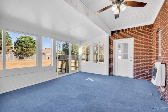 unfurnished sunroom featuring heating unit, vaulted ceiling, and ceiling fan