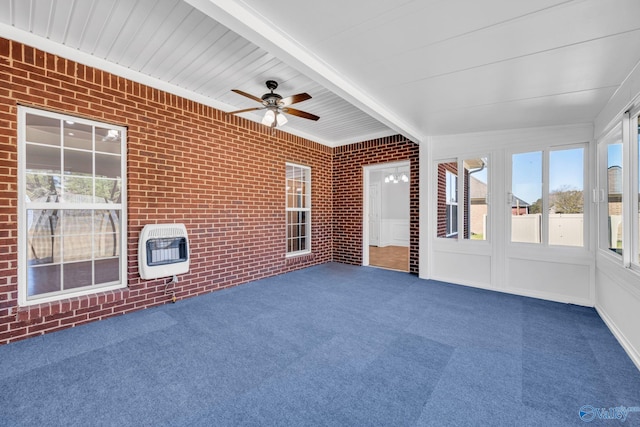 unfurnished sunroom with ceiling fan, beamed ceiling, and heating unit