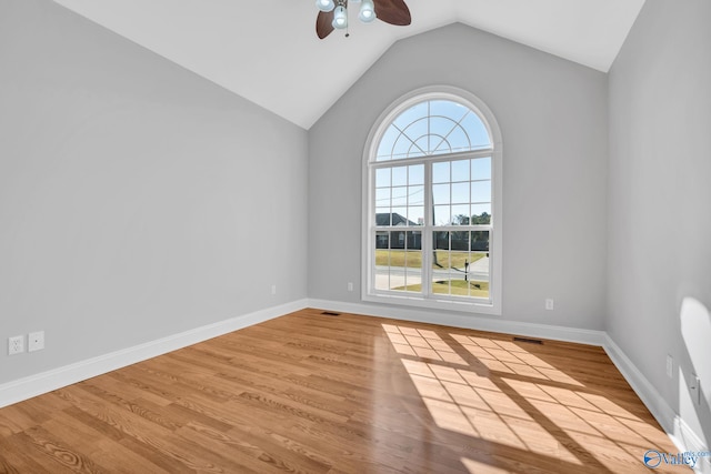 unfurnished room featuring light hardwood / wood-style floors, vaulted ceiling, a wealth of natural light, and ceiling fan