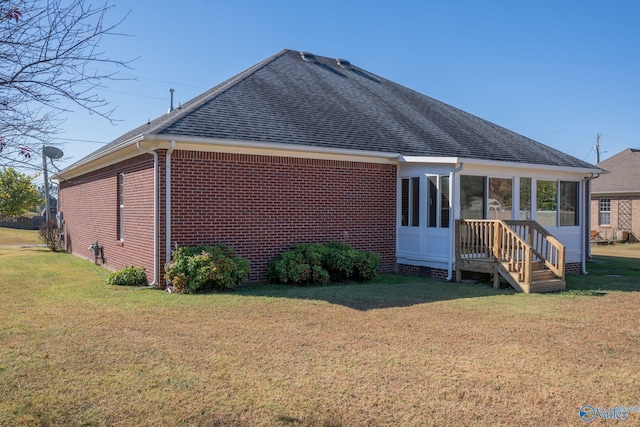 rear view of house featuring a yard and a sunroom