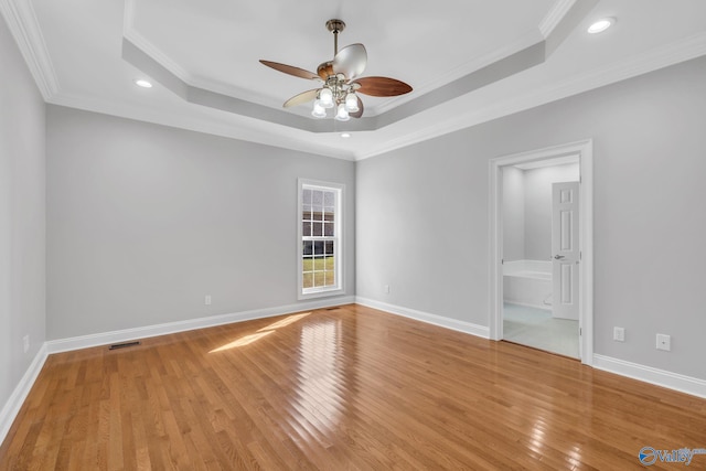 unfurnished bedroom featuring light hardwood / wood-style floors, ornamental molding, a tray ceiling, and ceiling fan